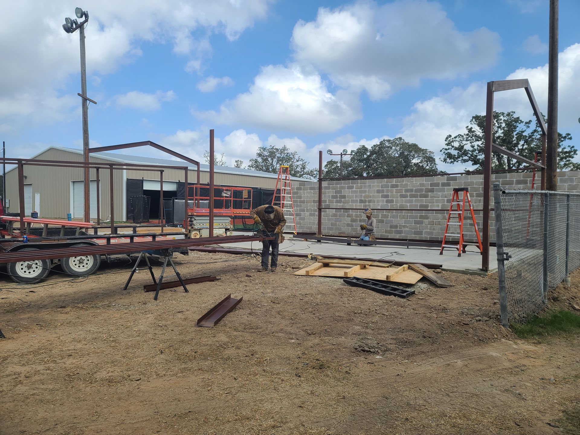 Construction site with workers, metal beams, and building materials.