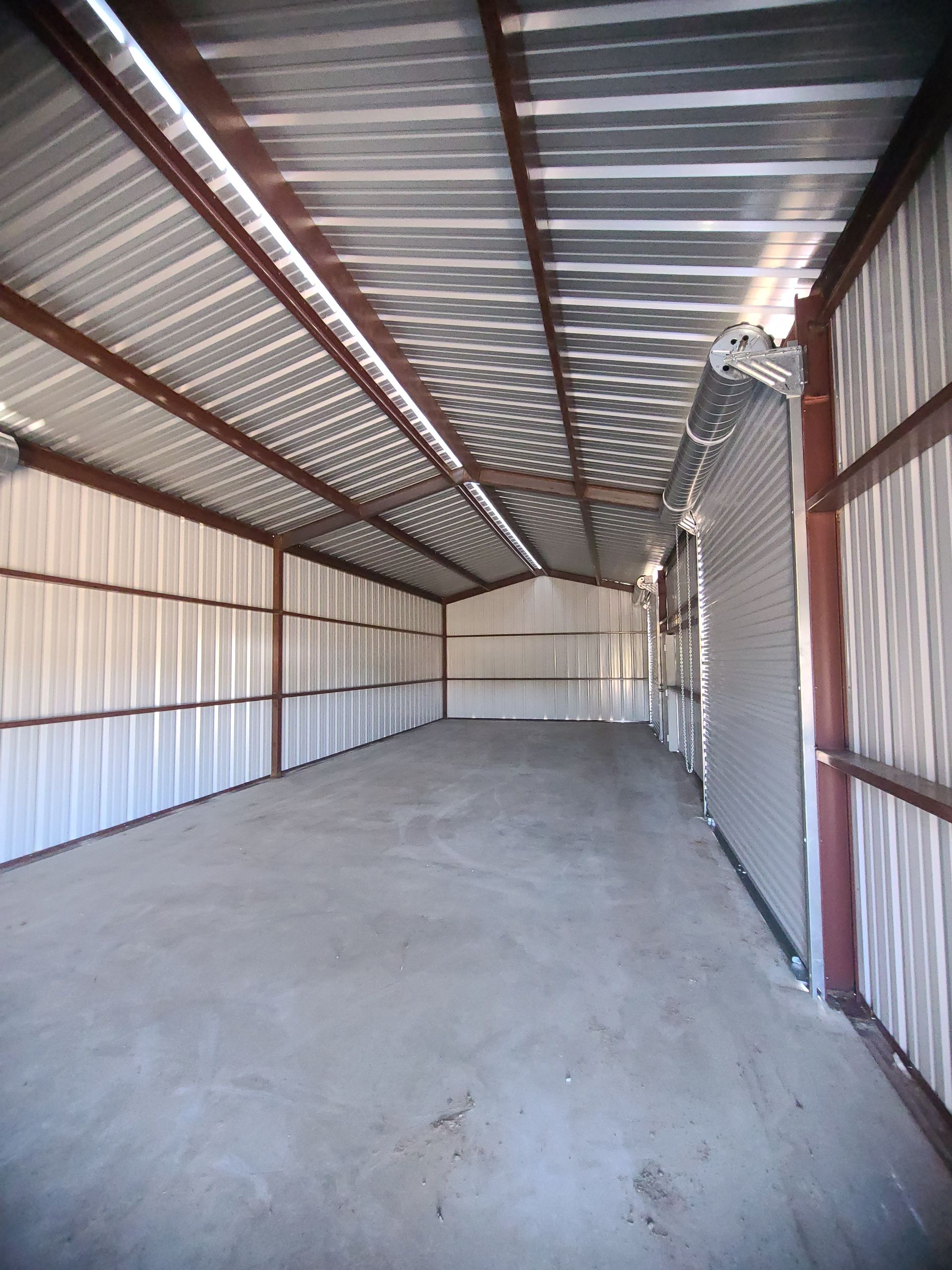 Interior of an empty metal storage shed with a concrete floor.