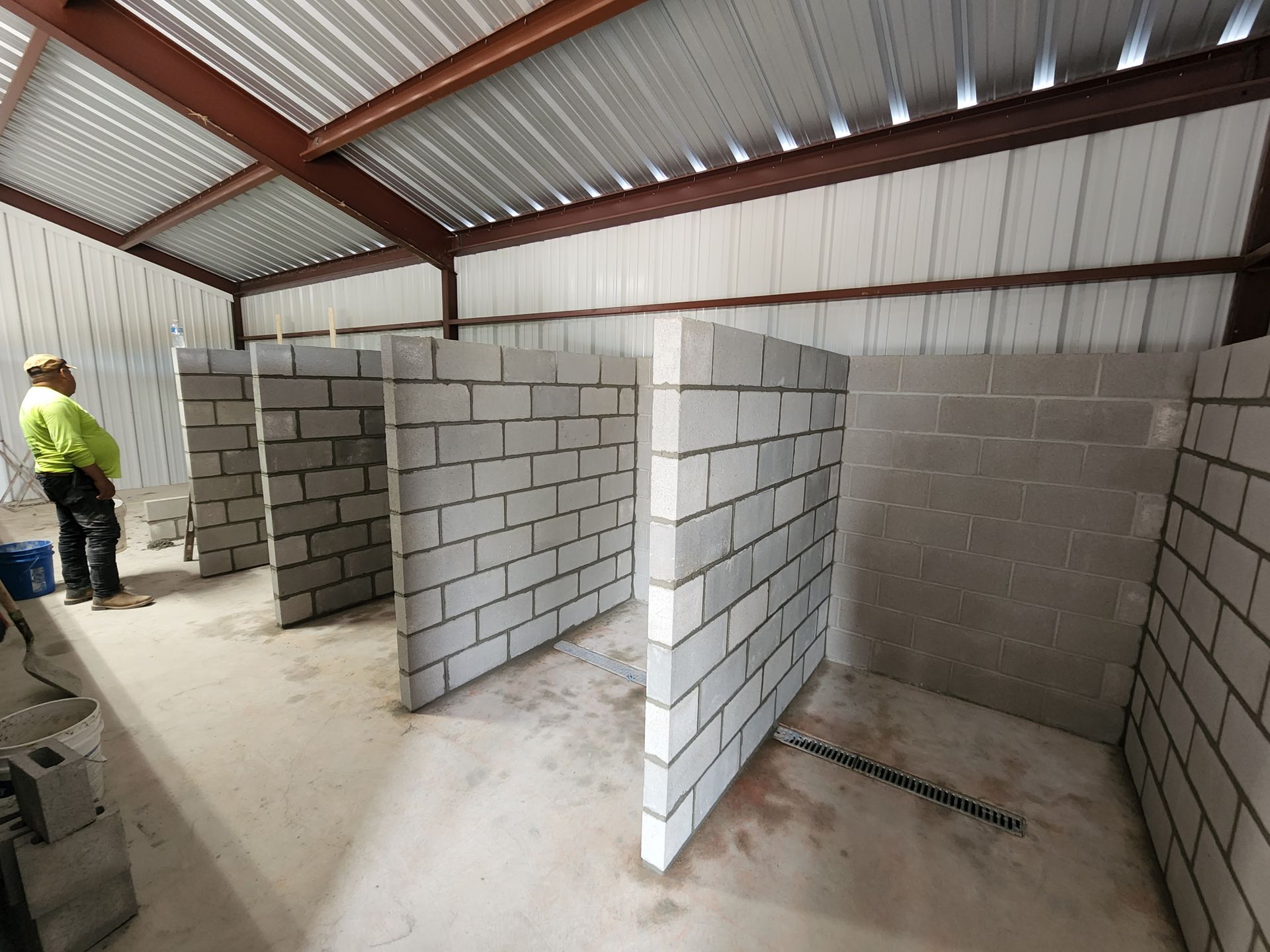 Construction worker standing in a building with cinder block walls, preparing for bathroom stalls.