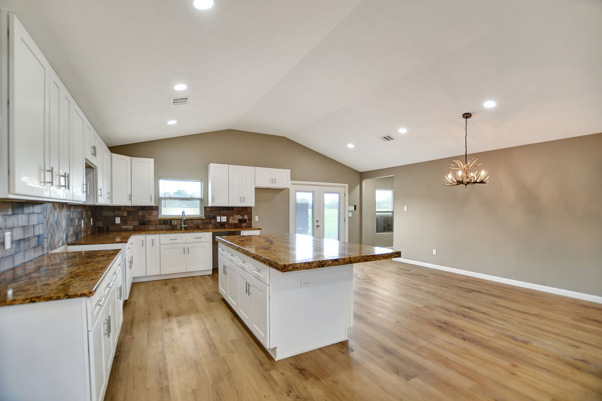 Modern kitchen with white cabinets, granite countertops, and hardwood floors.