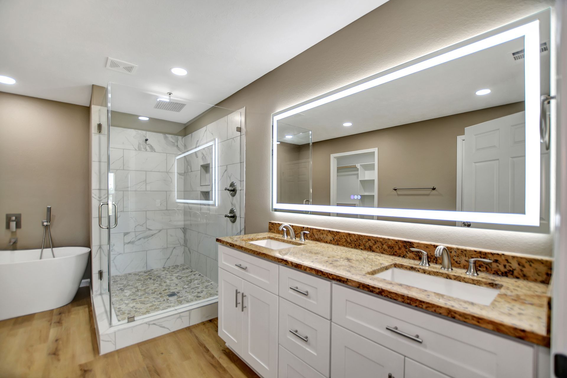 Modern bathroom with white vanity, large mirror, and glass shower.