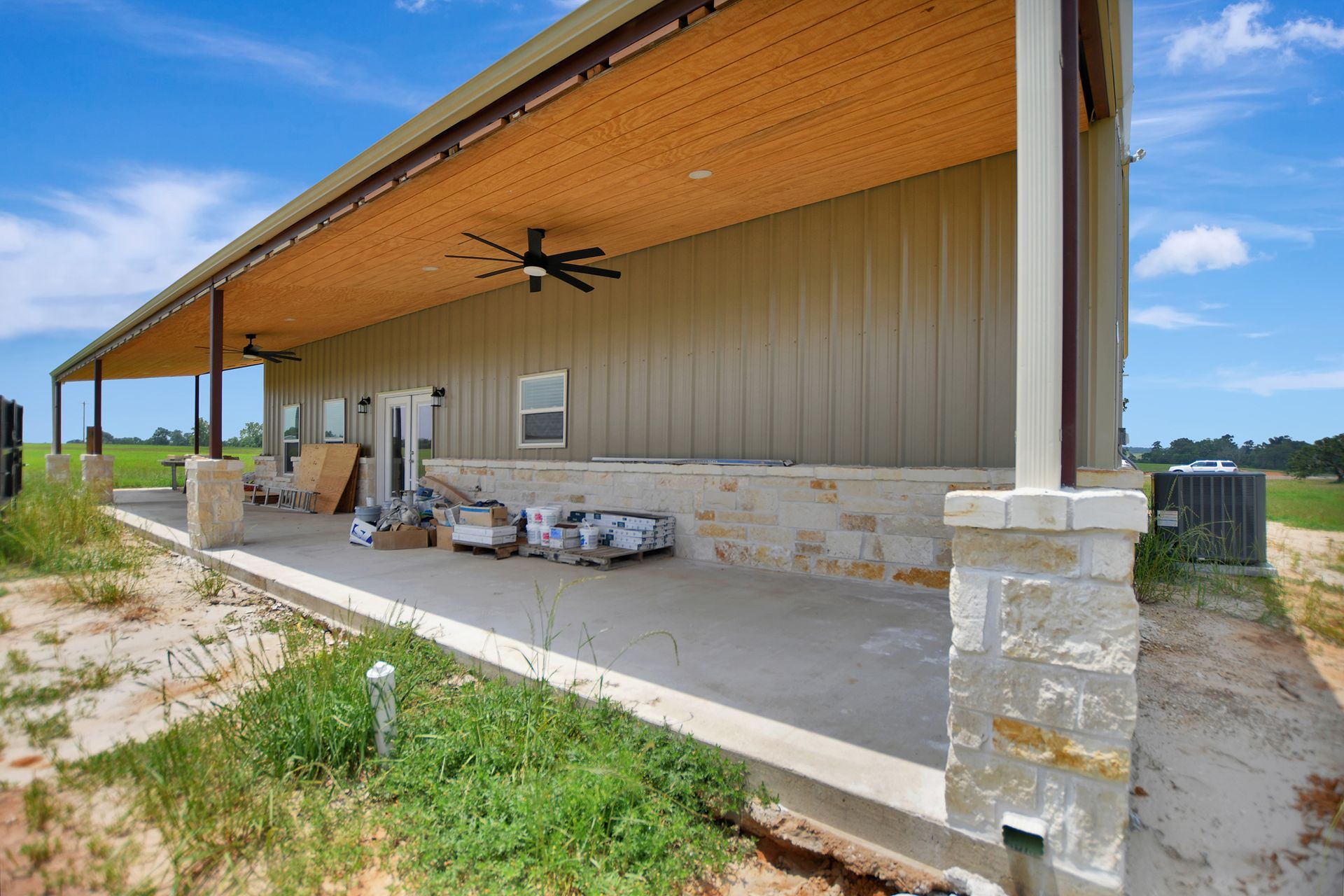 Building exterior with long porch, metal siding, and stone accents under a blue sky.