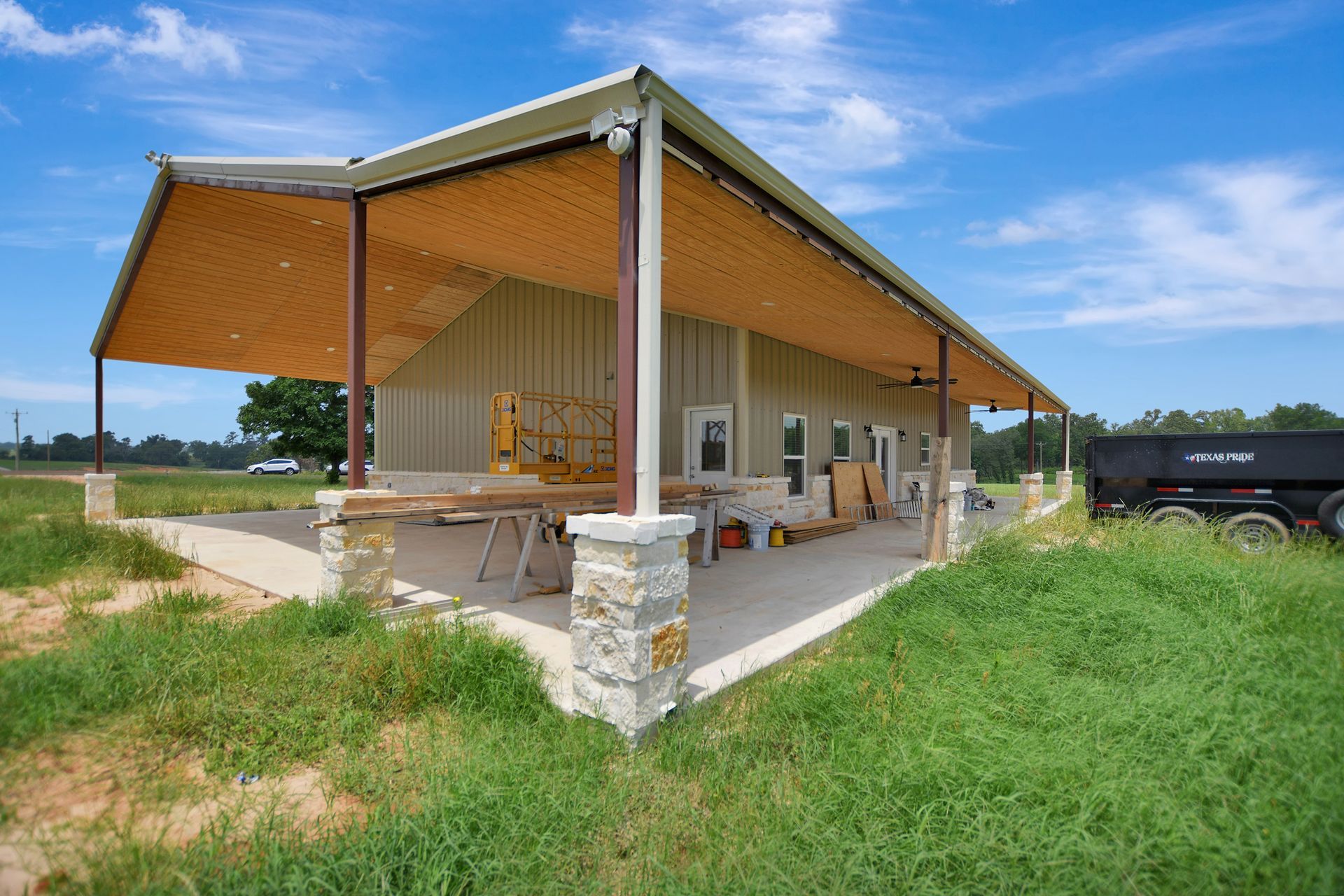 A beige building with a covered porch; set in a field under a blue sky.