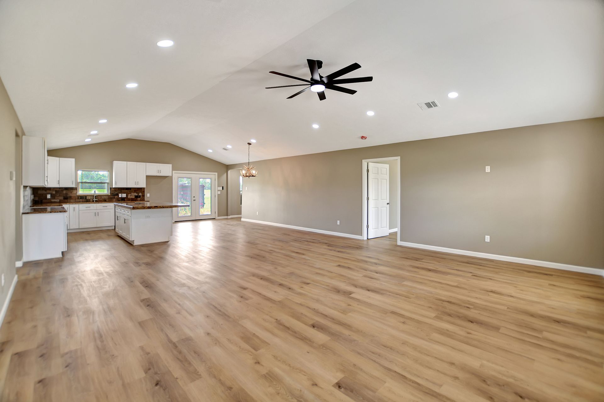 Spacious open-concept living area with kitchen, island, and wood-look floors.