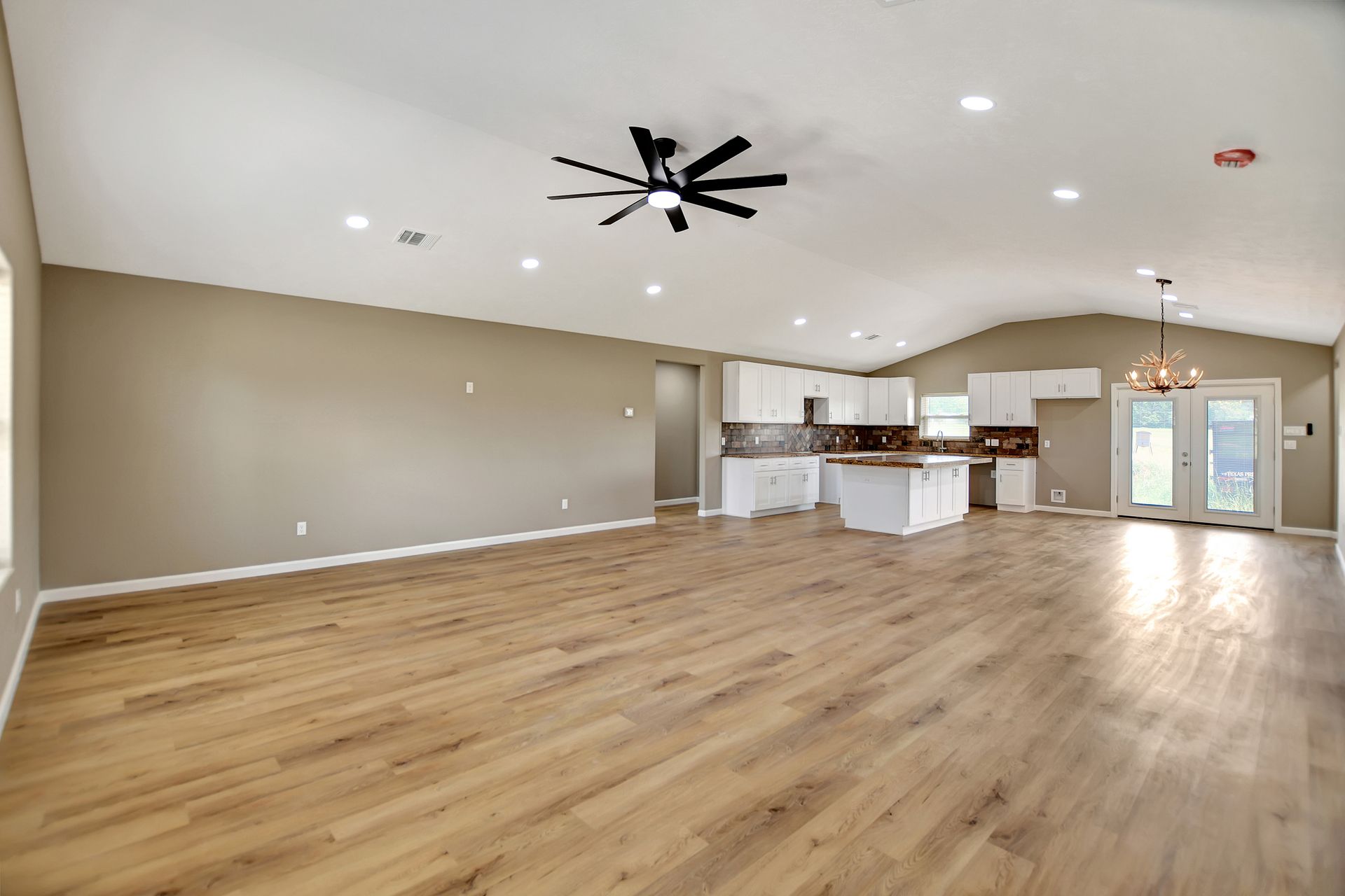 Spacious, open-plan living room and kitchen with hardwood floors and recessed lighting.