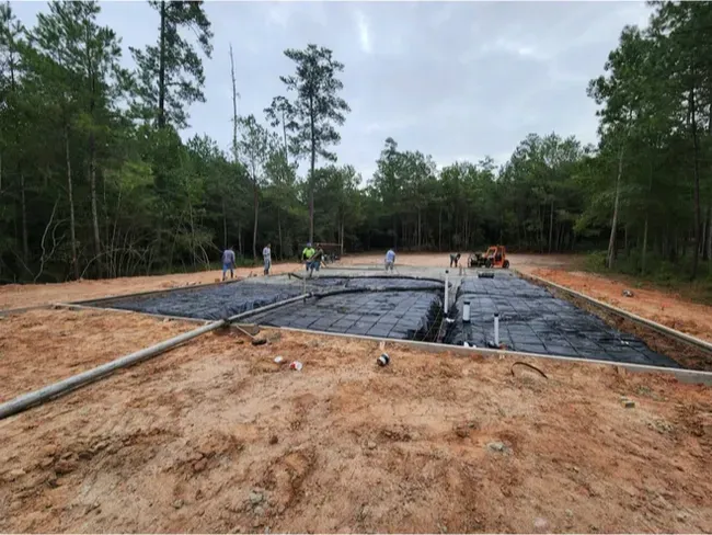 A construction site with a lot of dirt and trees in the background.