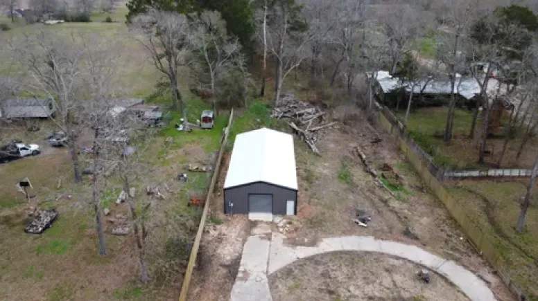 An aerial view of a garage in the middle of a field surrounded by trees.