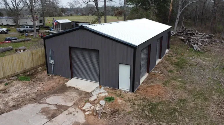 An aerial view of a metal garage with a white roof.