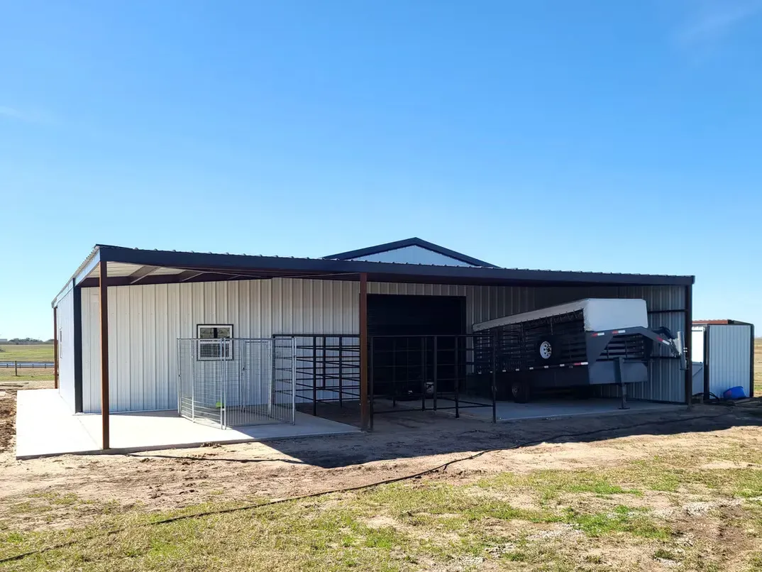 A large metal building is sitting in the middle of a grassy field.