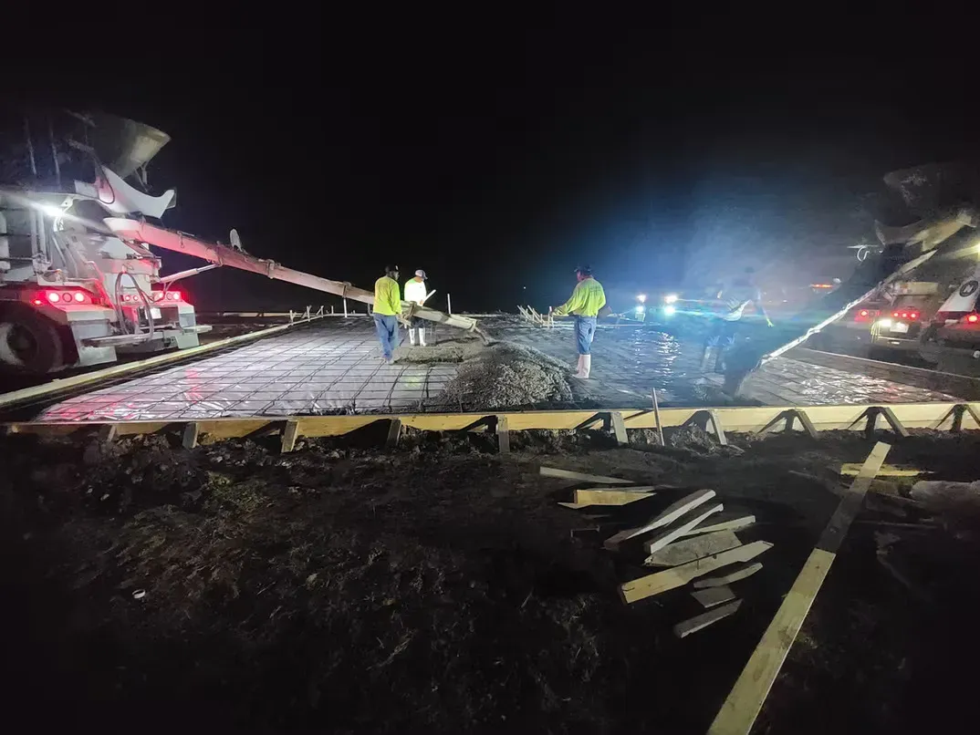 A group of construction workers are working on a road at night.
