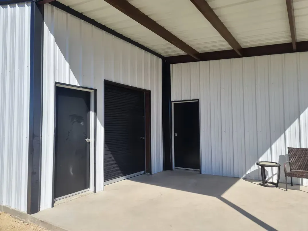 A white building with black doors and a covered porch.