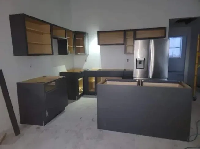 A kitchen under construction with a stainless steel refrigerator