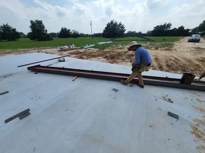 A man wearing a cowboy hat is standing on a concrete surface.