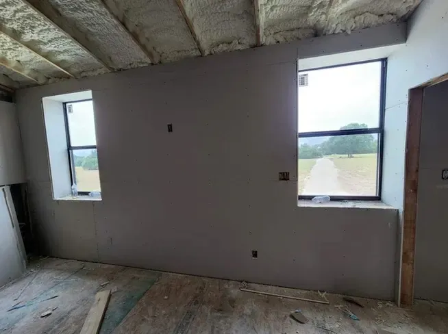 A room with two windows and a ceiling that is being built.