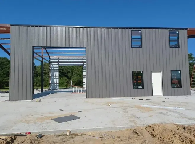 A large metal building is being built with a large garage door.