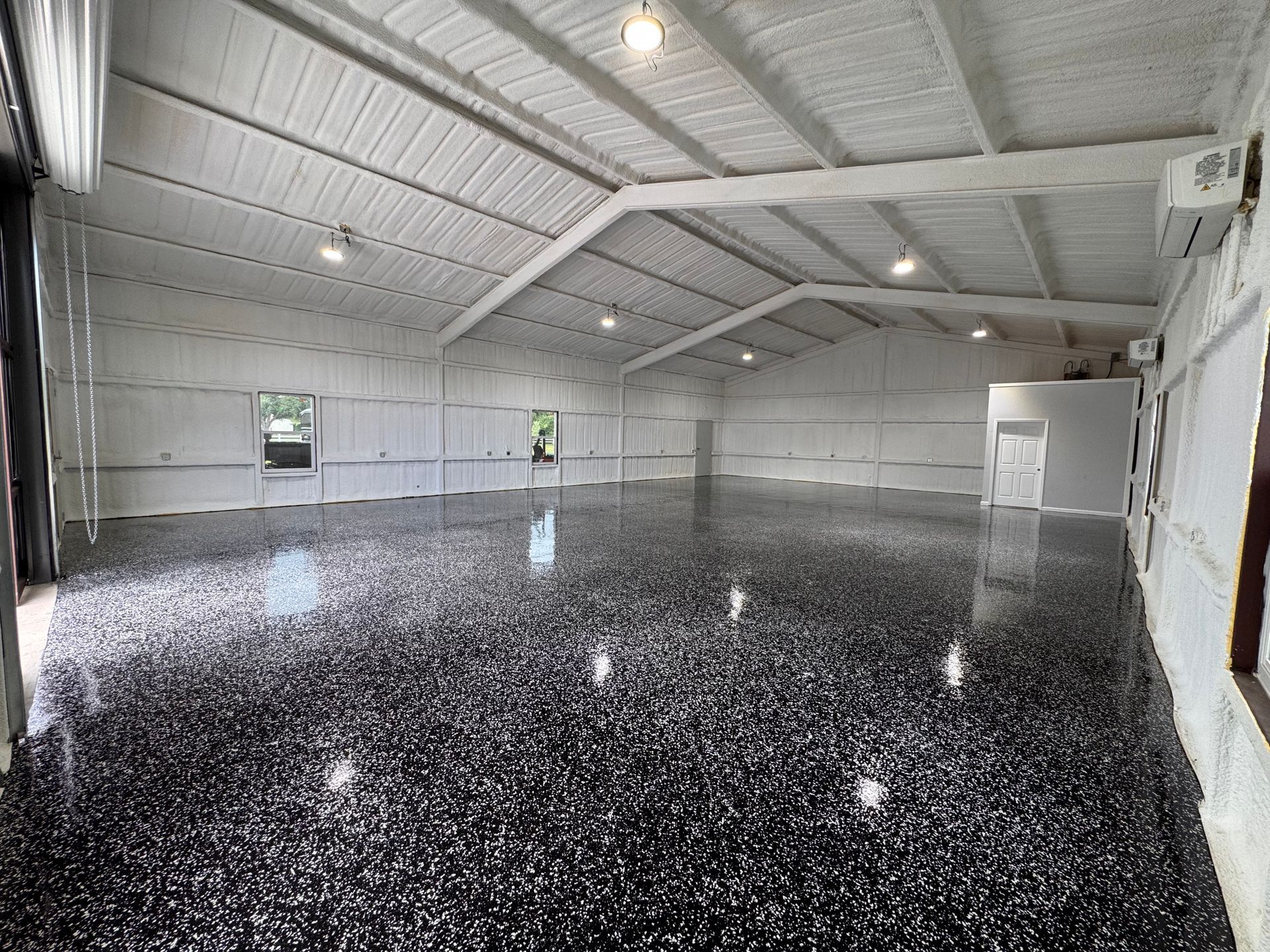 Empty warehouse interior with glossy black floor and white walls/ceiling.