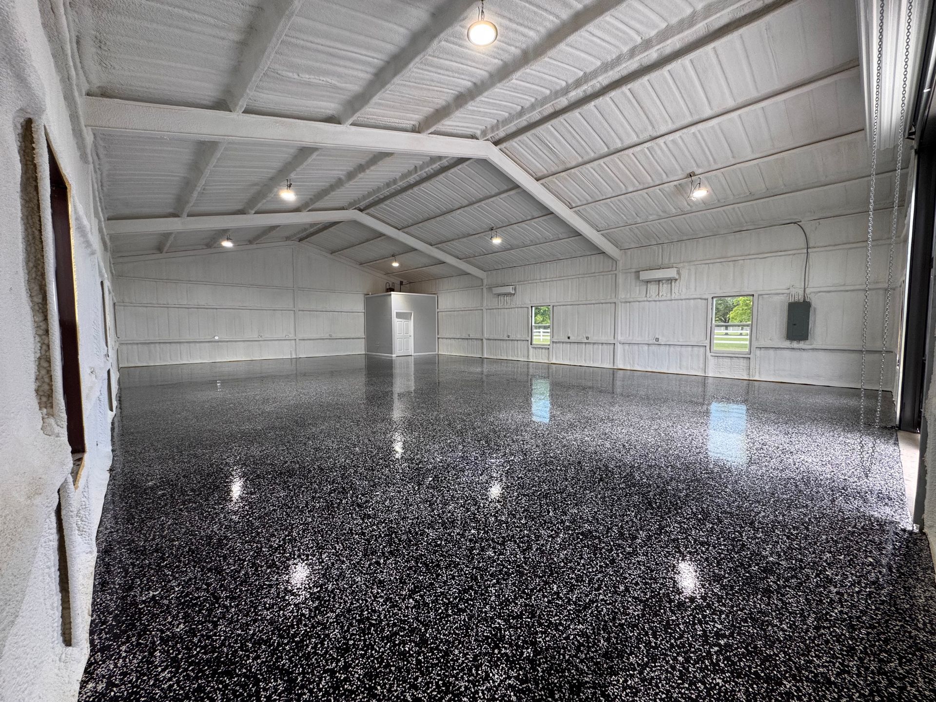 Inside a bright white industrial building with a black and silver speckled, glossy floor.