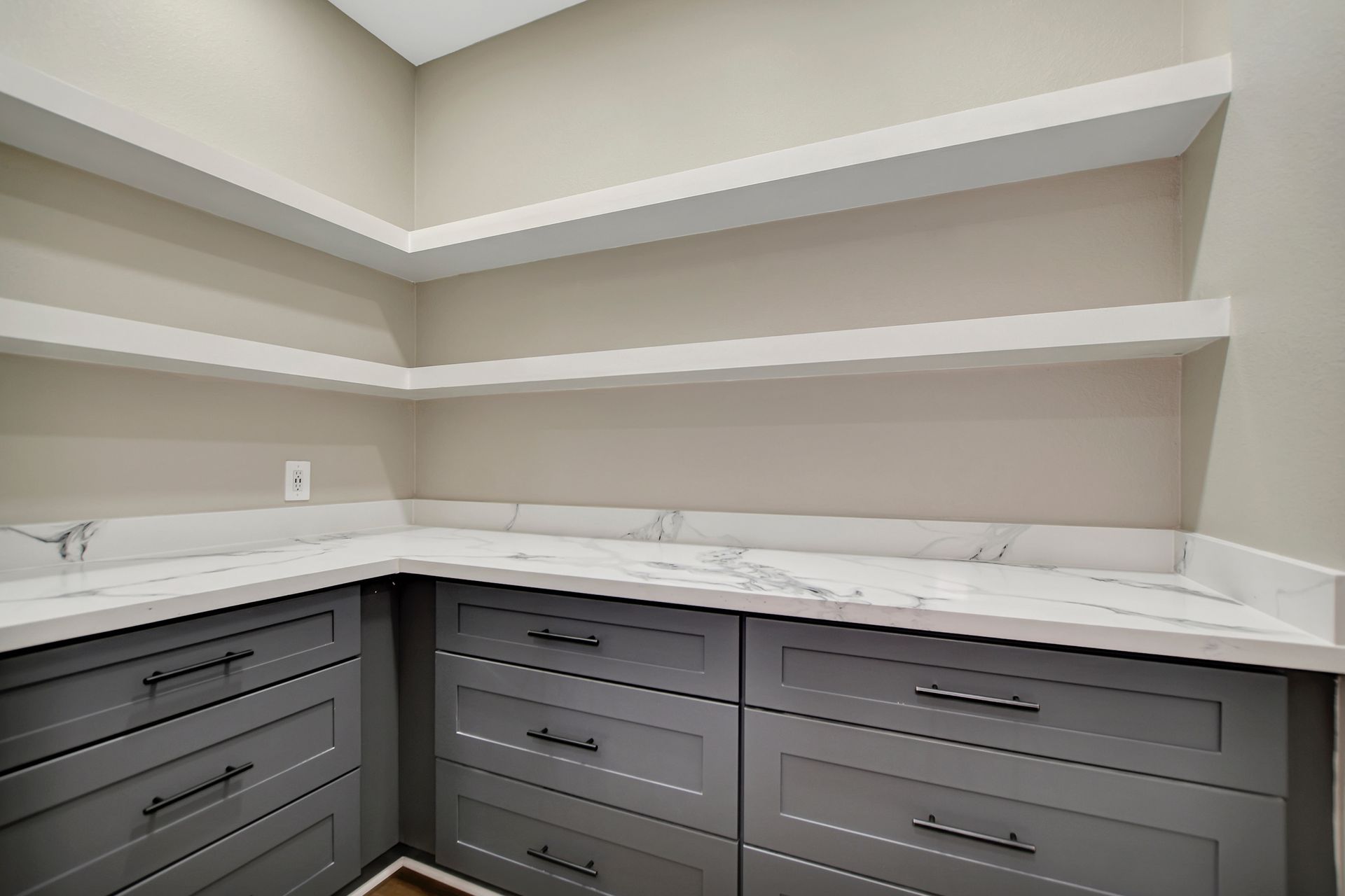 Gray cabinets, white countertop and shelves, empty pantry.