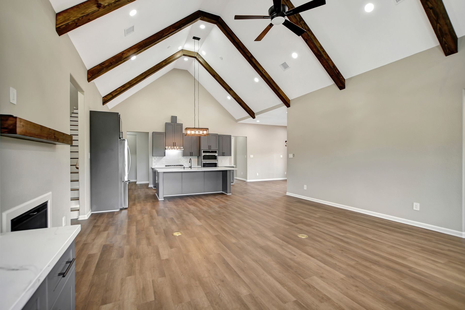 Interior of a modern home with a vaulted ceiling, wood beams, and gray kitchen.