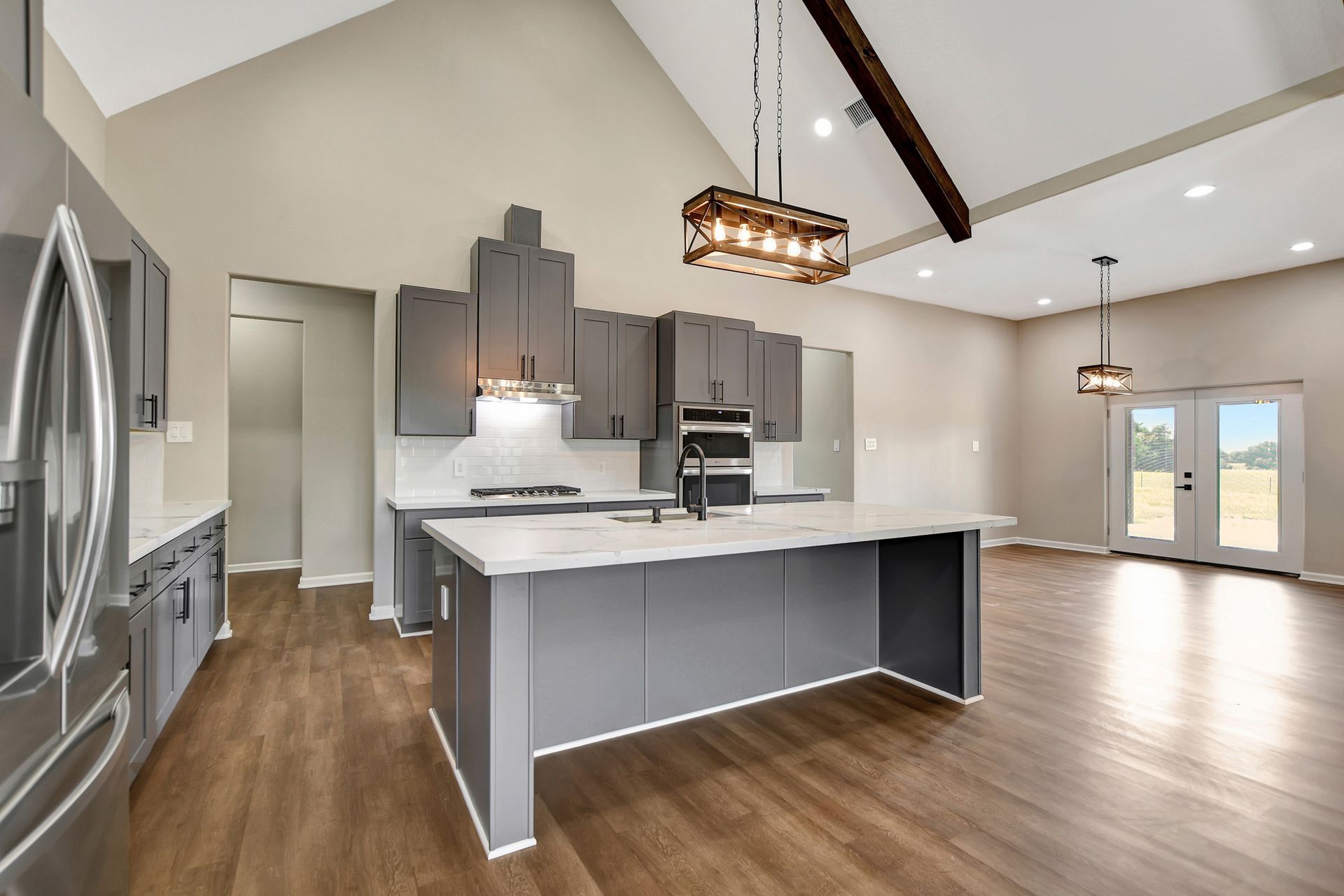 Modern kitchen with gray cabinets, white countertops, and wooden floors.