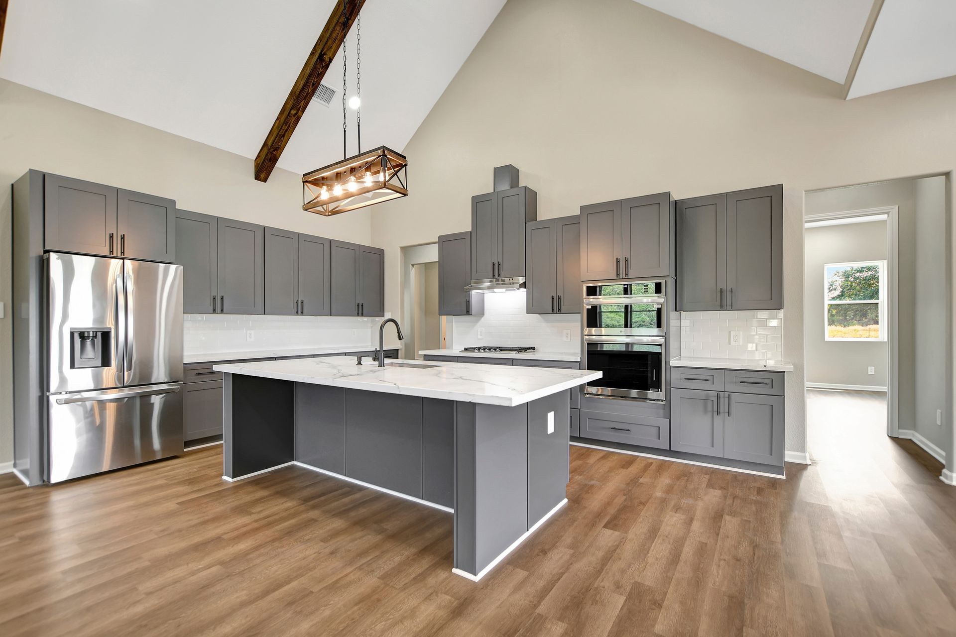 Modern kitchen with gray cabinets, white countertops, stainless steel appliances, and wood flooring.