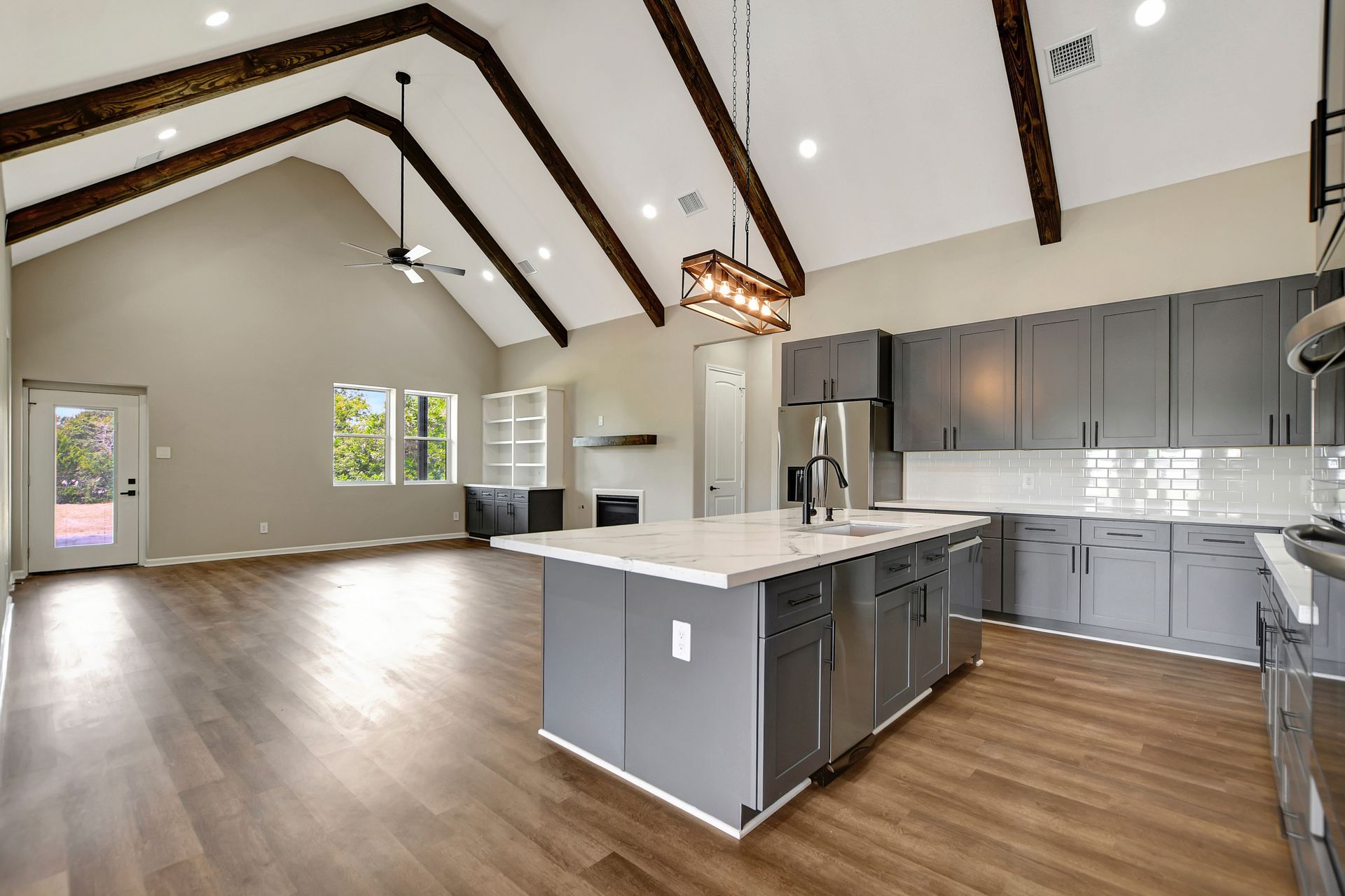 Spacious kitchen with gray cabinets, large island, and wood beams on the vaulted ceiling.