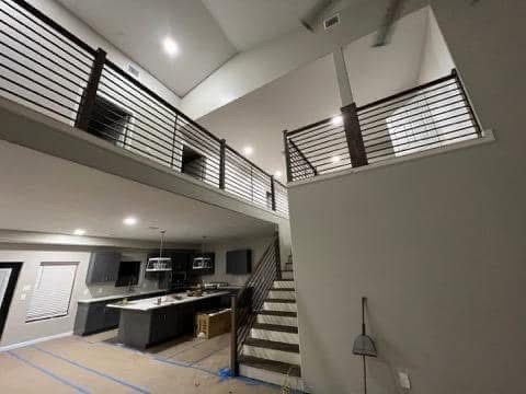 Modern home interior with a loft, stairs, and sleek black railings.