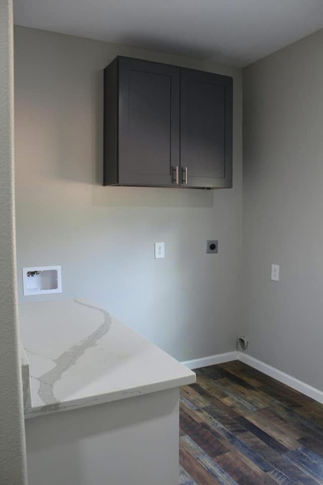 Laundry room with grey walls, cabinetry, counter, and wood-look flooring.