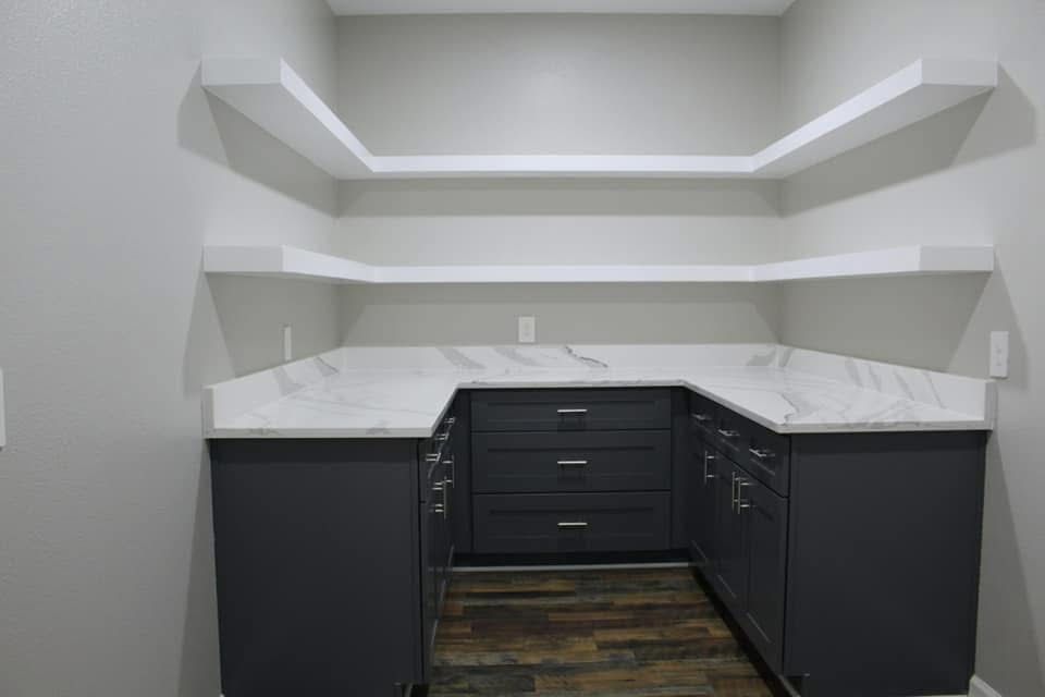 Gray and white built-in pantry with shelves, countertops, and cabinets.