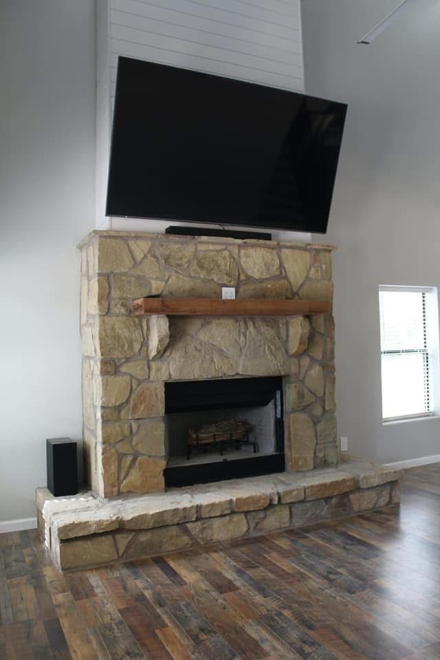 Stone fireplace with a large TV mounted above.
