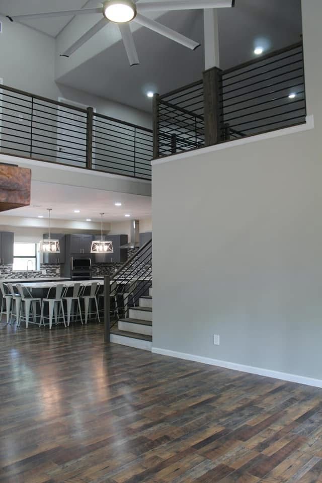 Modern home interior with wood floors, open kitchen, loft, and staircase.