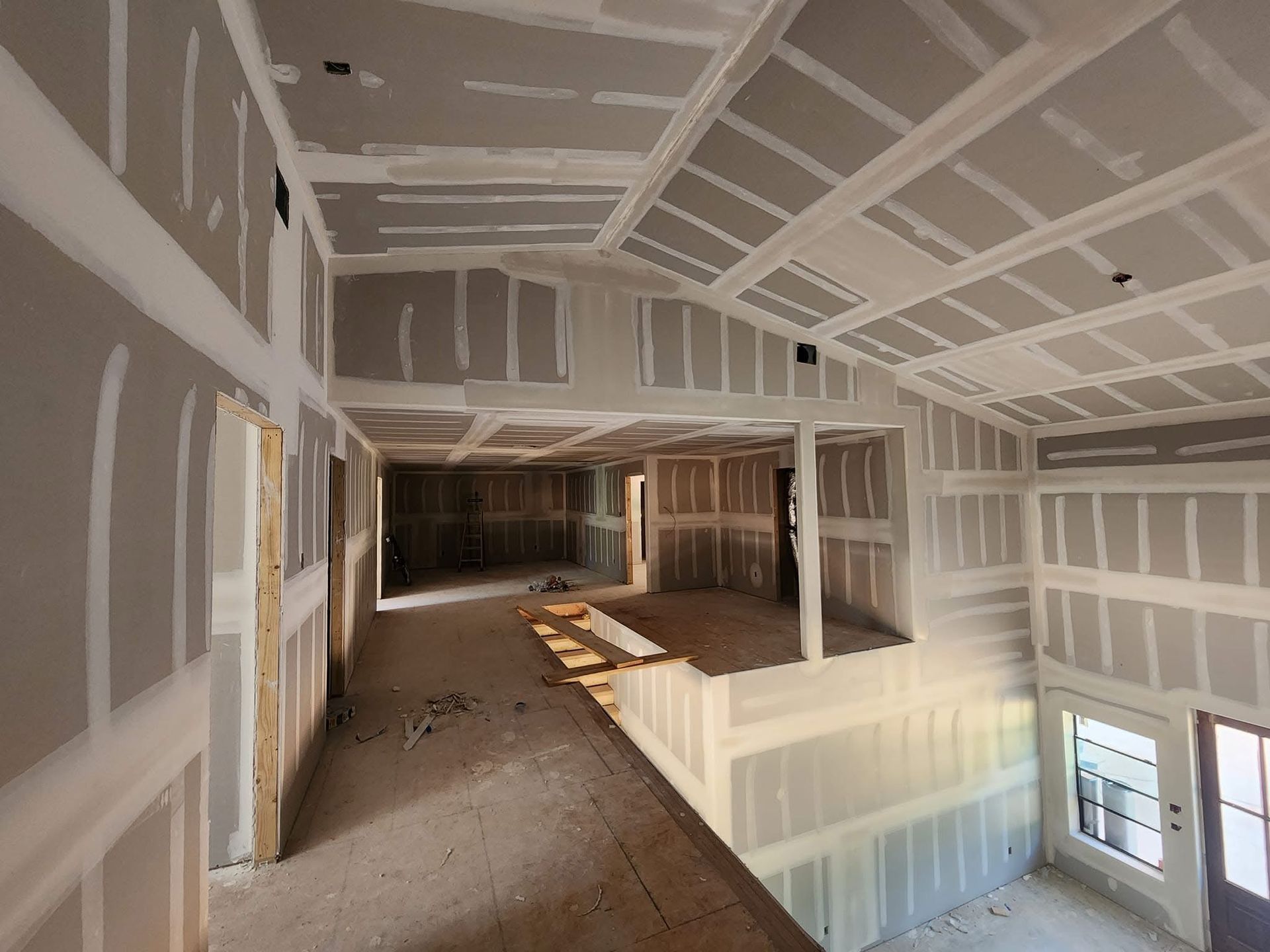 Interior of a house under construction; drywall installation on walls and ceiling.