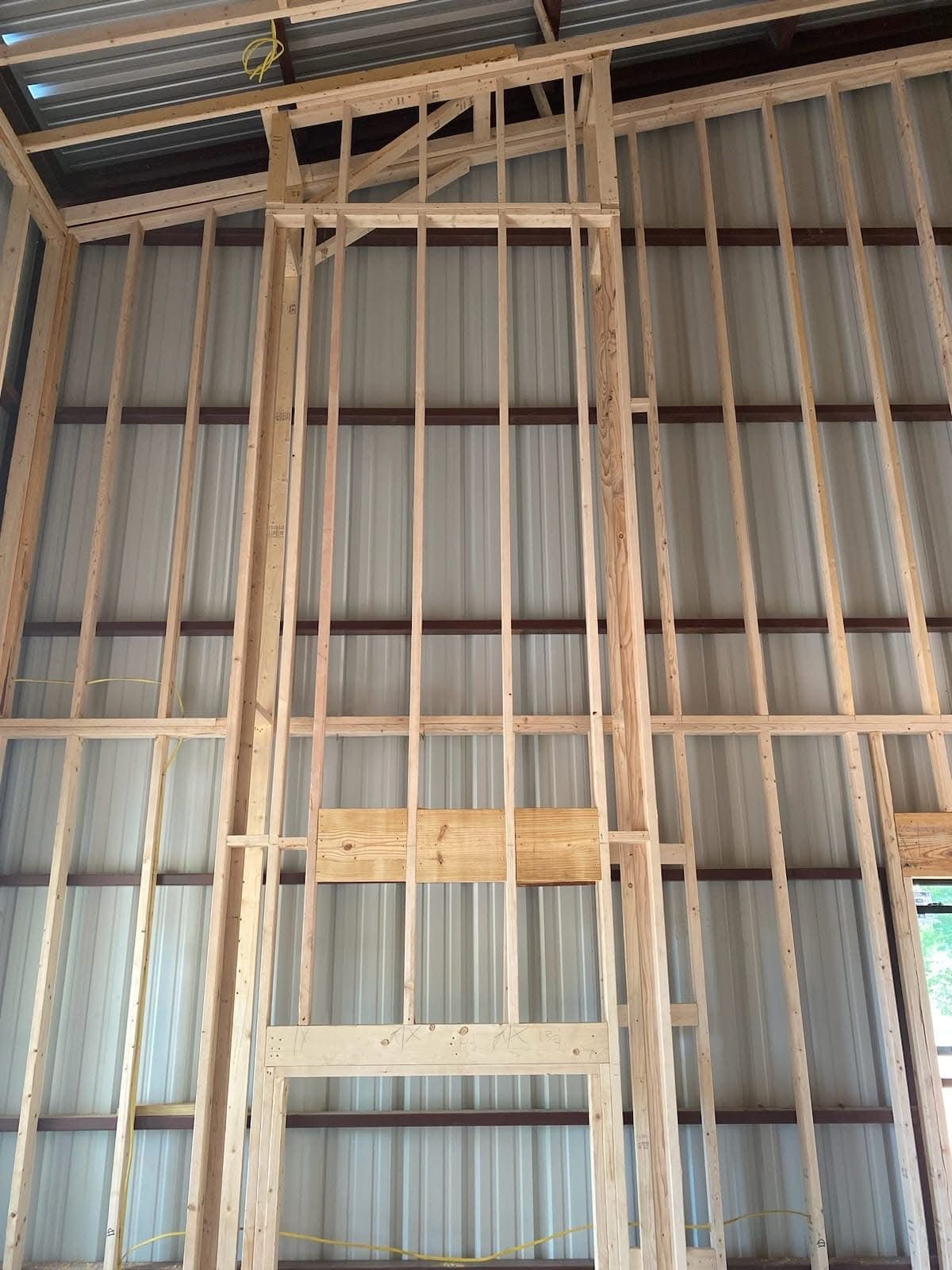 Wooden framing against a metal wall inside a building, likely under construction.