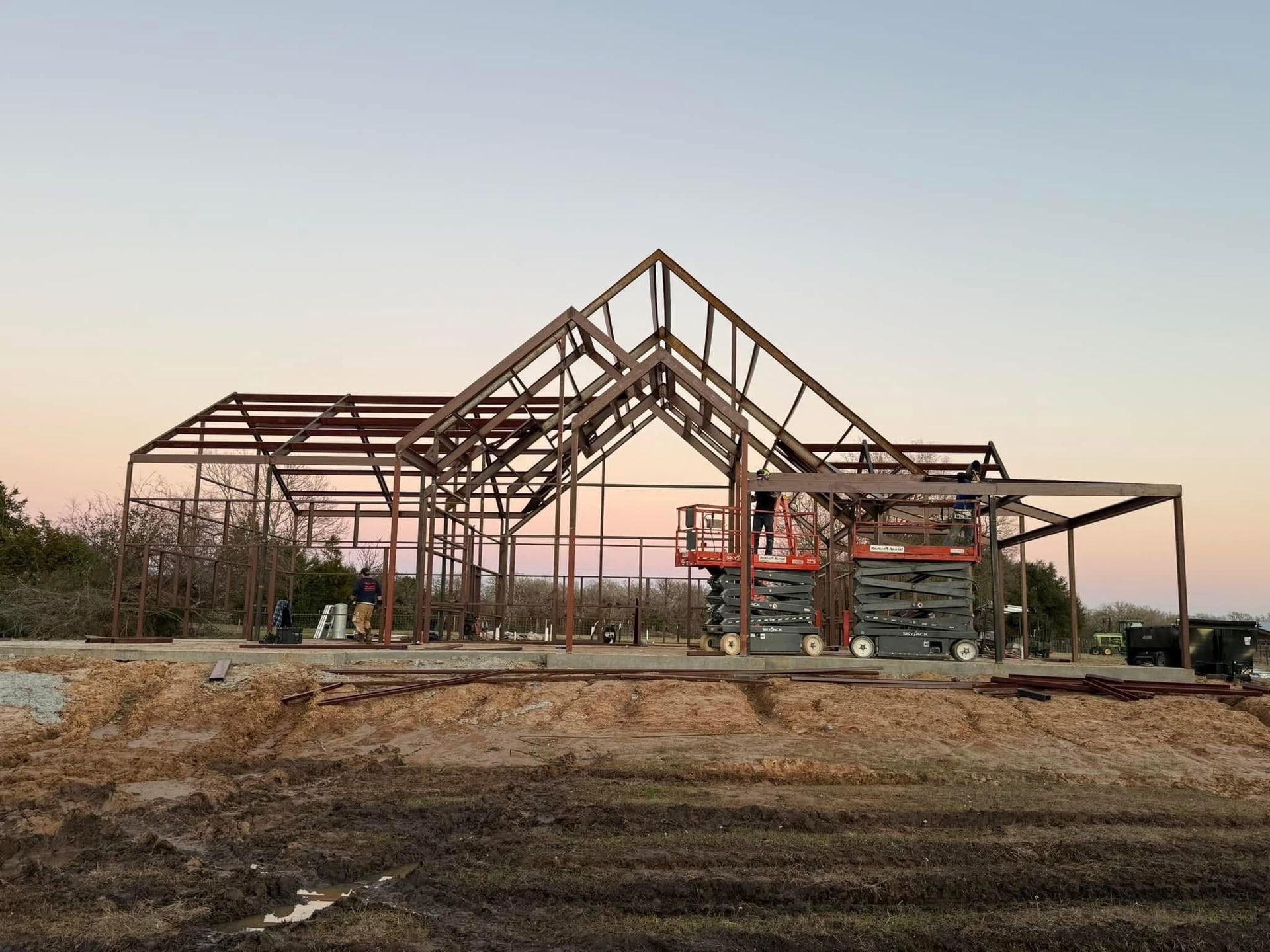 Steel framework of a building under construction against a dusk sky.