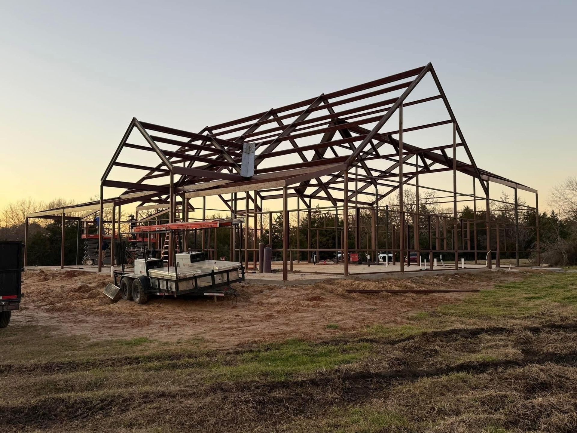 Steel frame of a barn under construction in a field; brown and tan colors dominate the scene.