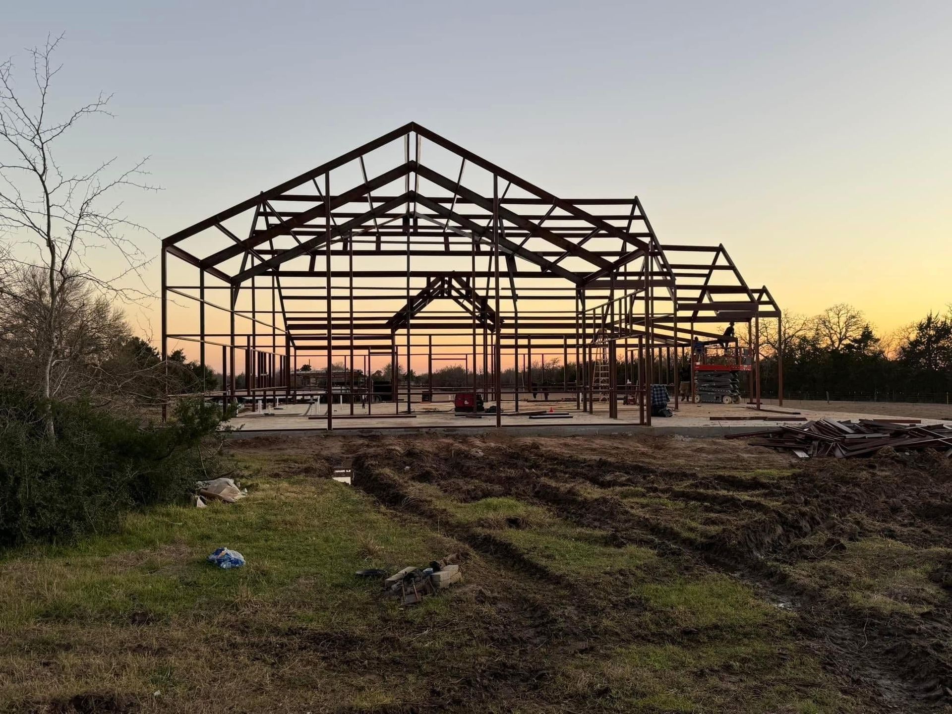 Steel frame of a building under construction against a twilight sky.