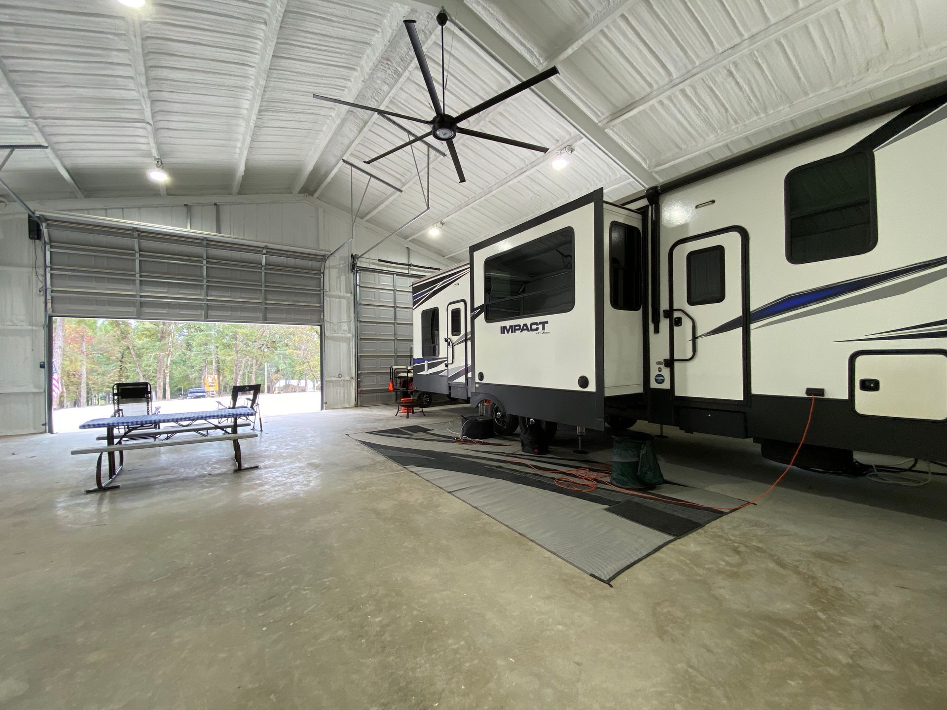 RV parked inside a large, open metal building with a picnic table.