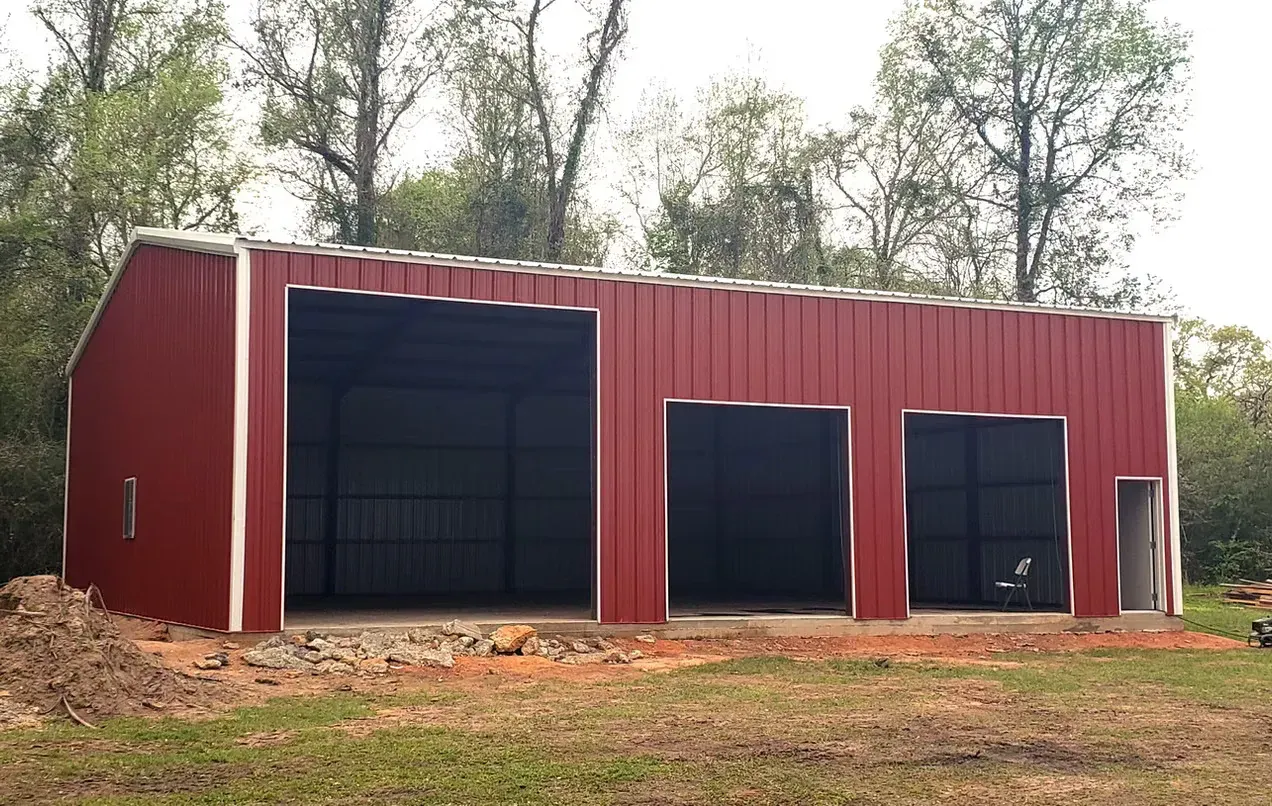A large red barn is sitting in the middle of a grassy field.