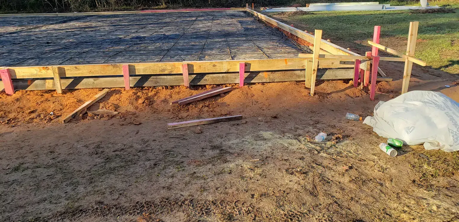 A concrete foundation is being built on a dirt field.