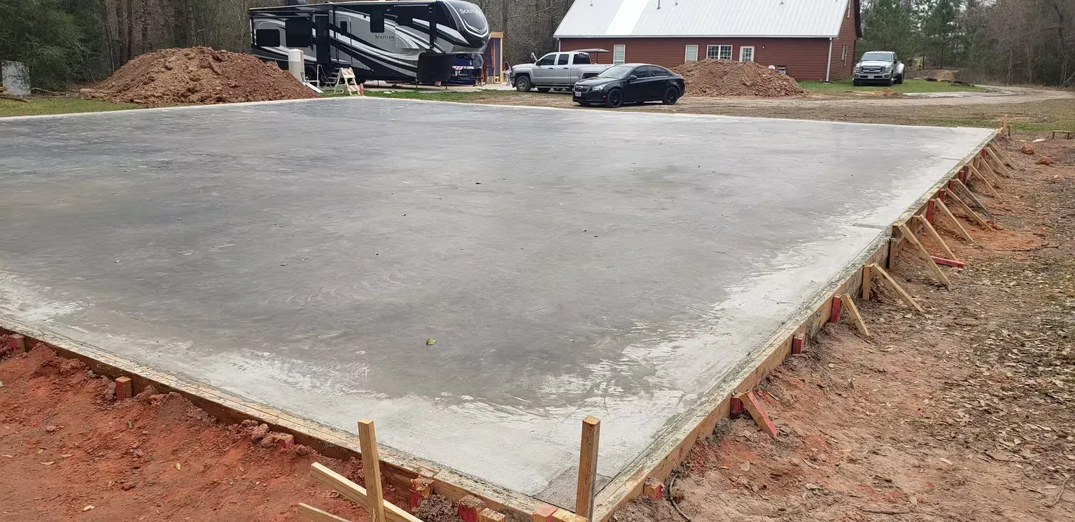 A large concrete slab is being poured in front of a house.