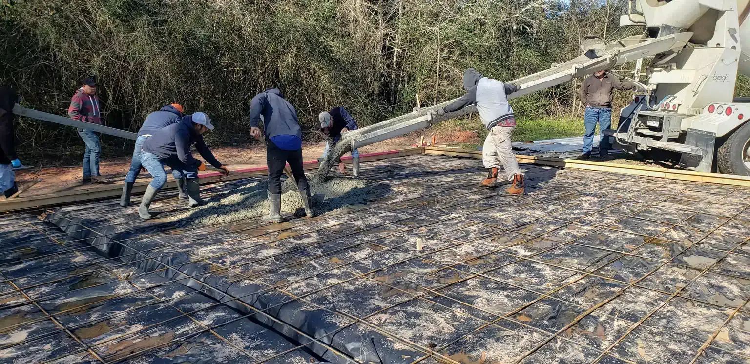 A group of construction workers are working on a concrete floor.