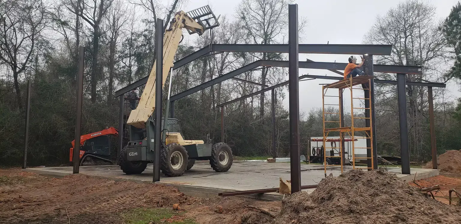 A man is standing on a ladder in front of a building under construction.