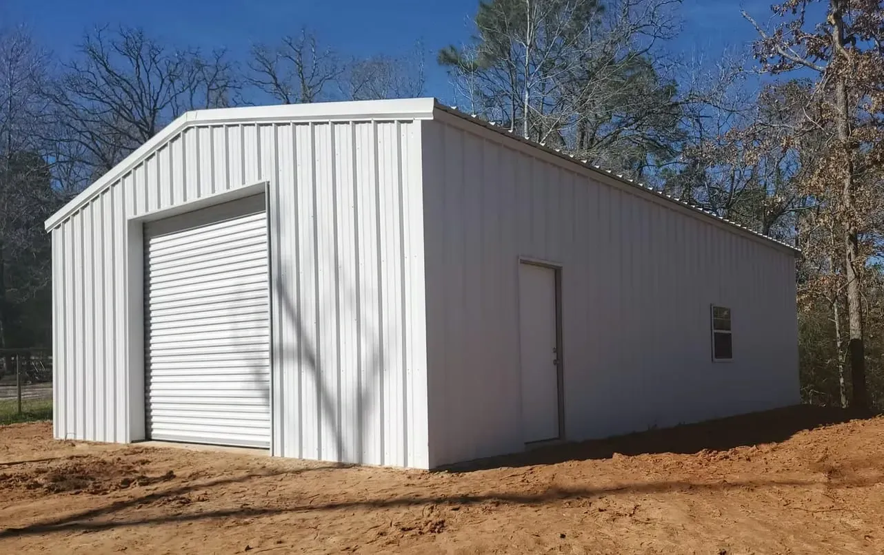 A white metal garage is sitting on top of a dirt hill.