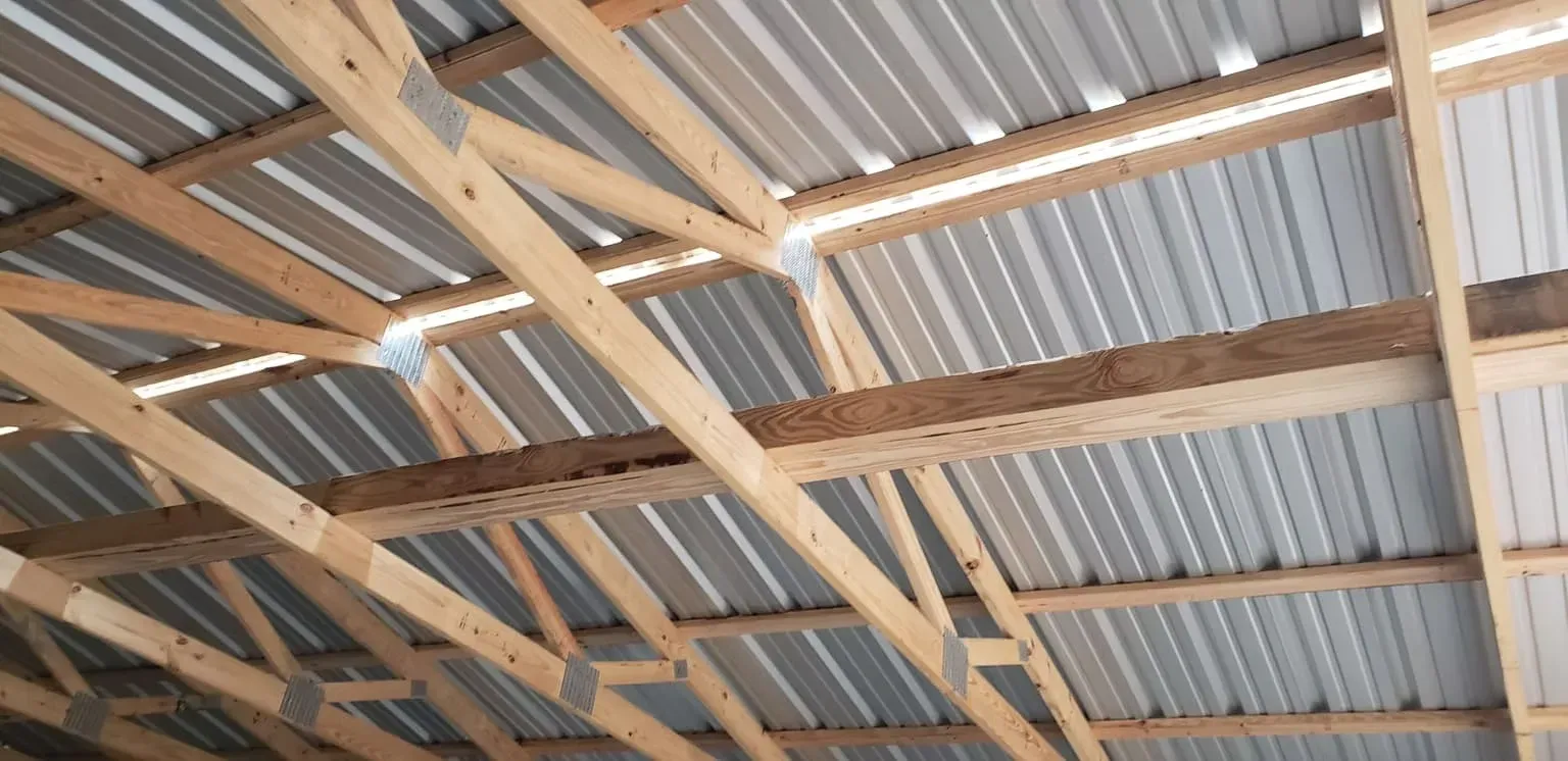 The ceiling of a building with wooden beams and a metal roof.