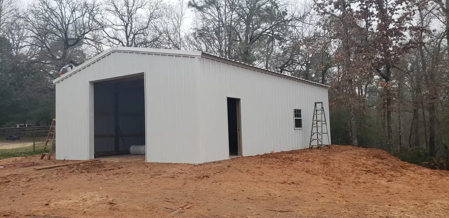 A white garage is sitting on top of a dirt hill.
