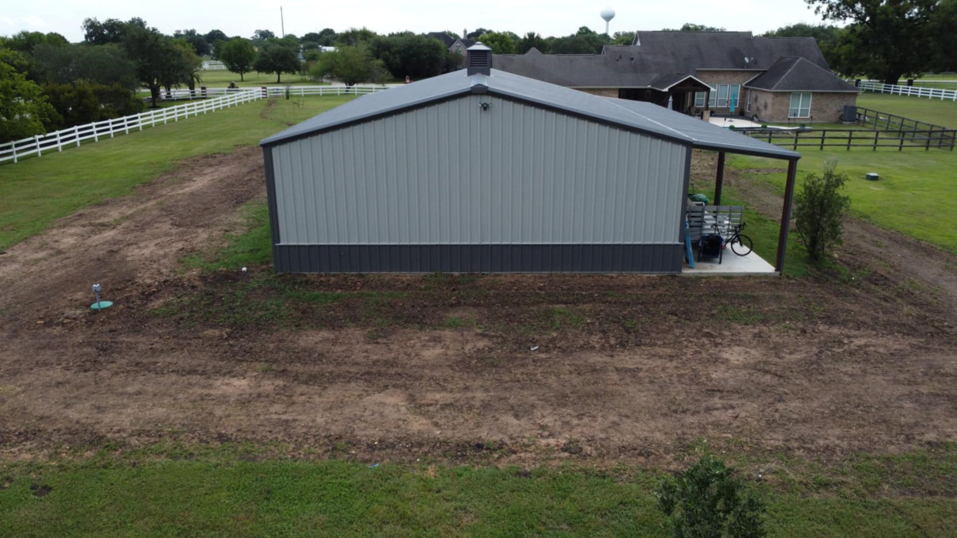 Gray metal building with a dark grey base and small covered patio on a grassy lot.