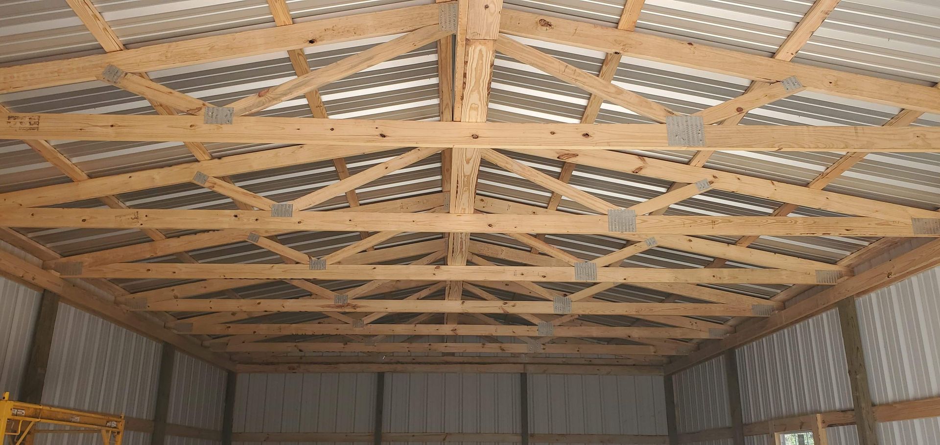 Interior of a metal building with wooden rafters and metal roof.