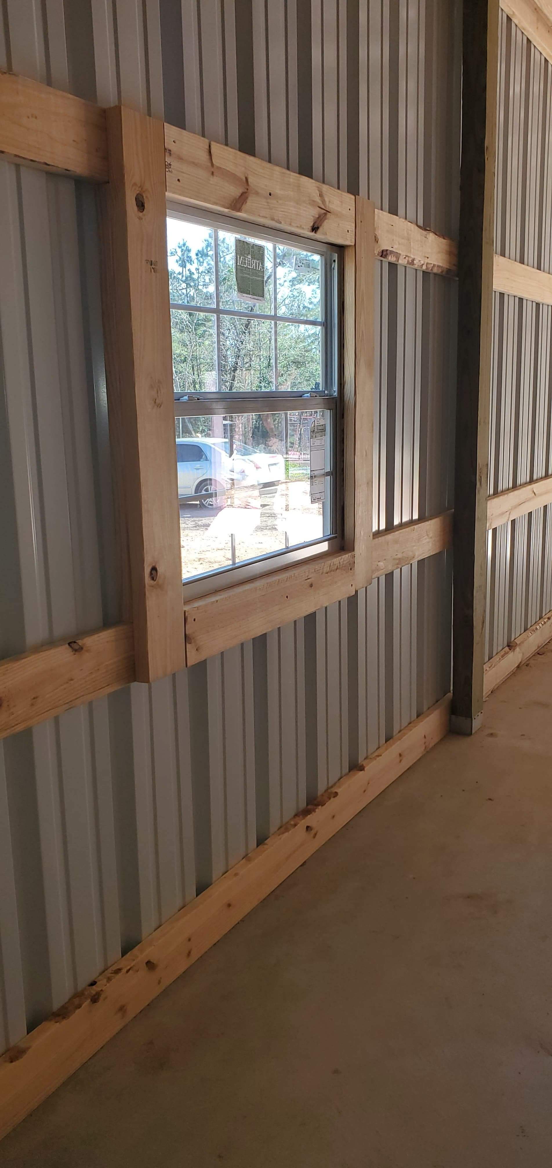 Interior view of a building with corrugated metal walls. A window is framed by wooden beams.