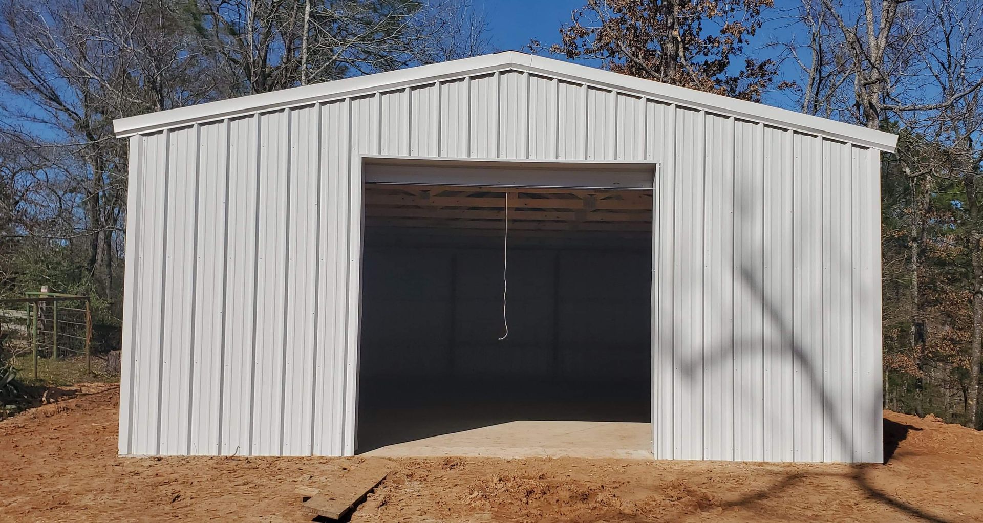 White metal shed with open entrance on a dirt lot.