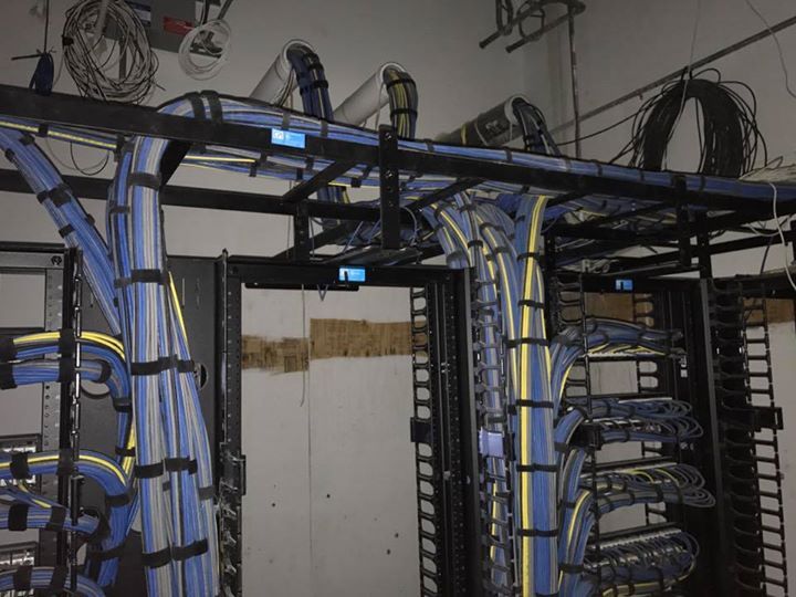 Network cables running through black cable trays and racks in a server room.